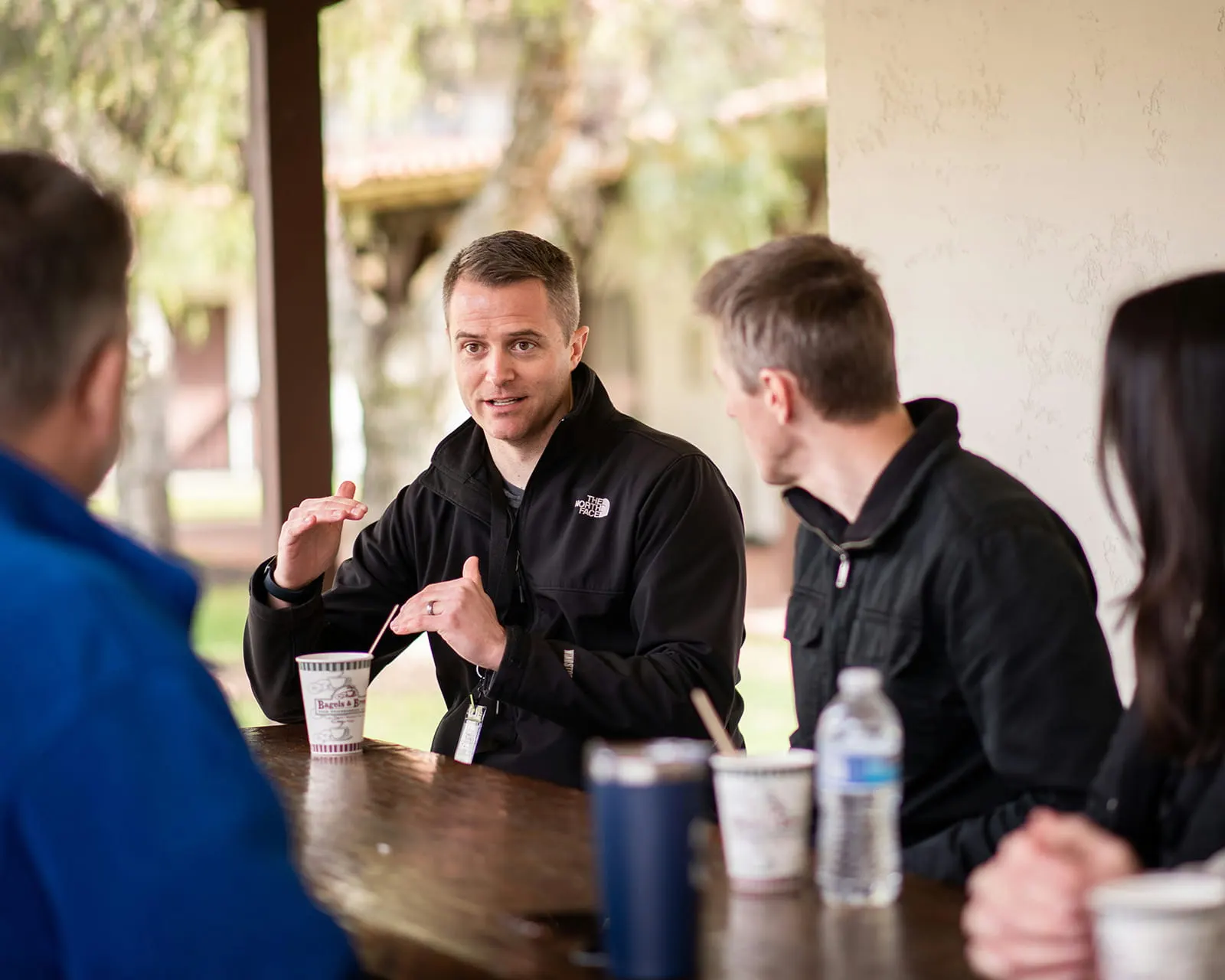 A small group talking over coffee at an outdoor table