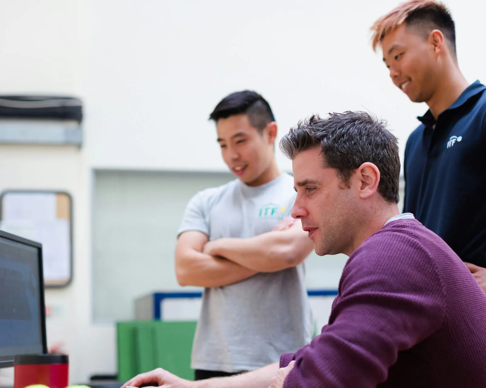 Three colleagues reviewing software together on a desktop monitor