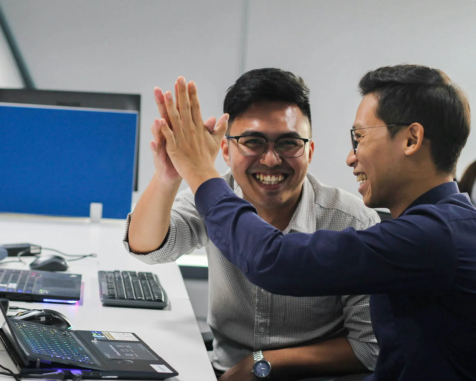 Two colleagues high-fiving at their desks