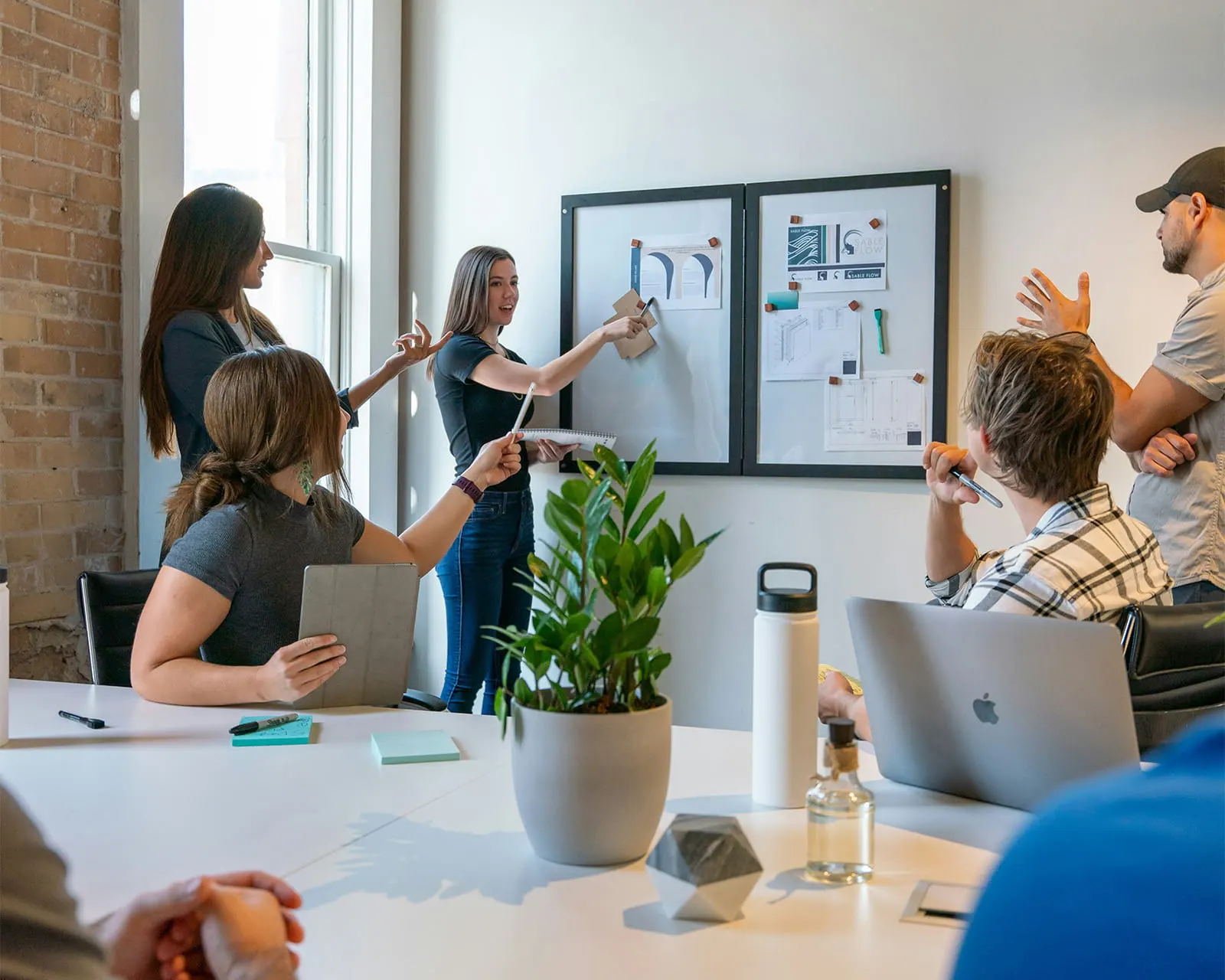 A team discussing design documents pinned to a board in a bright meeting room