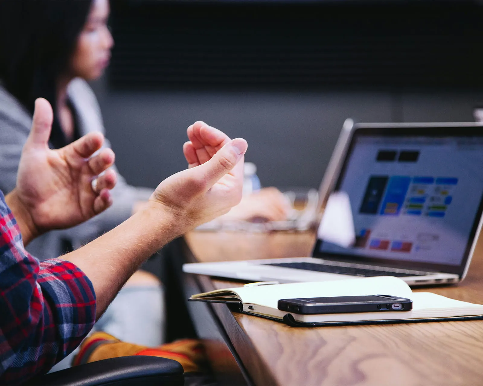 Hands gesturing during a planning meeting, with a website layout open on a laptop